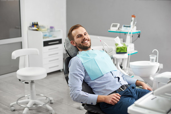 A smiling man in a dental chair after a scaling and root planing procedure from Fairbanks Periodontal Associates in Fairbanks, AK