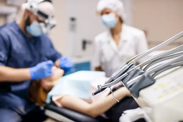 A close-up view of dental tools with a dentist and assistant performing a dental implant procedure at Fairbanks Periodontal Associates in Fairbanks, AK